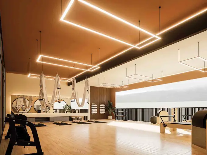 Gimnasio con máquinas, piso de madera e iluminación lineal